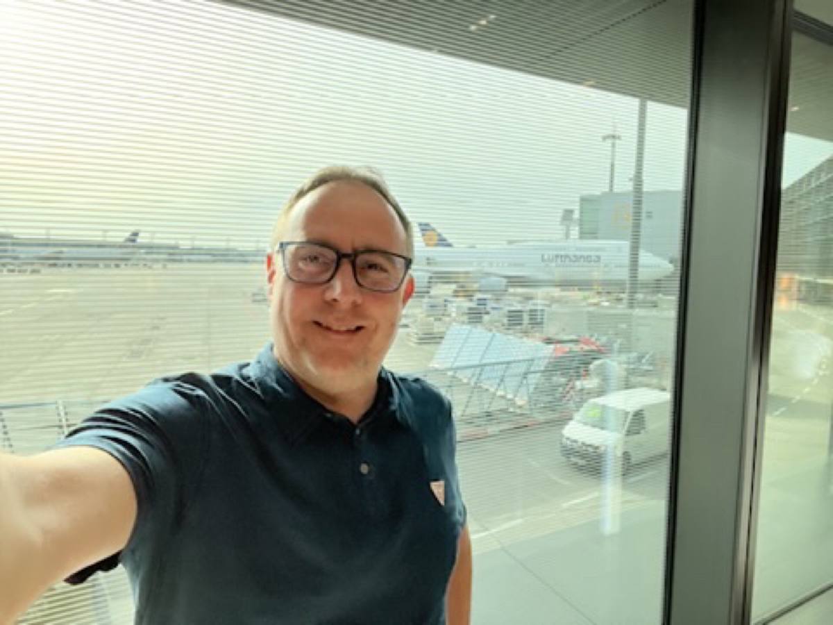 Thomas am Flughafen-Gate vor dem Flugzeug
